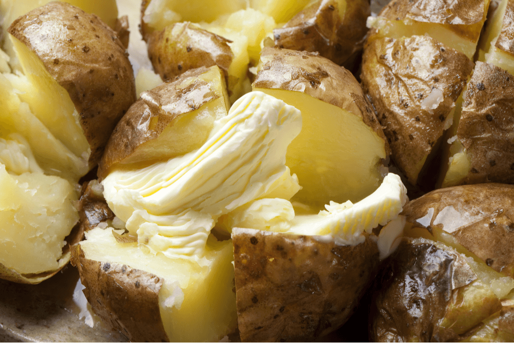 A close up of baked potatoes and a dairy condiment, also known as jagabata.