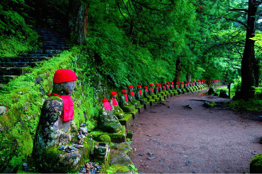 A row of stone Jizo statues near tress in Kanmangafuchi Abyss in Nikko, Japan.