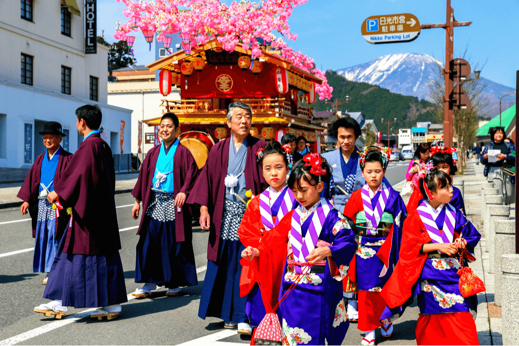 A bunch of people in tradtional Japanese garb strolling on a downtown Nikko street in the spring.