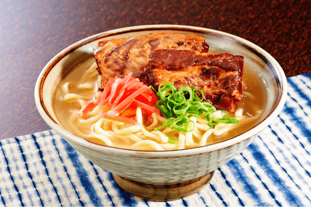 A bowl of Okinawan soba with roasted pork and ginger on top.