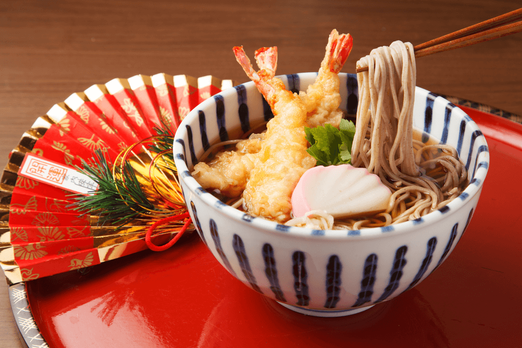 A bowl of toshikoshi soba on a red New Years plate.