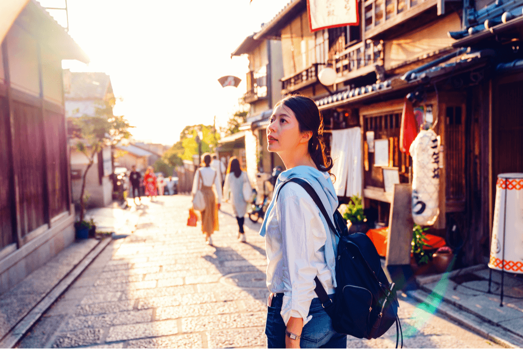 A woman looking around in a street that depicts a tradiitonal Japanese Tokyo lifestyle.