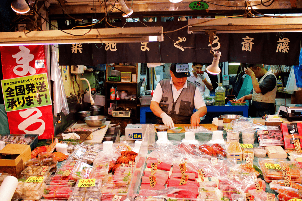 A fishmonger handles his stock of fish in the Tsukiji Fish Market. Image via Shutterstock