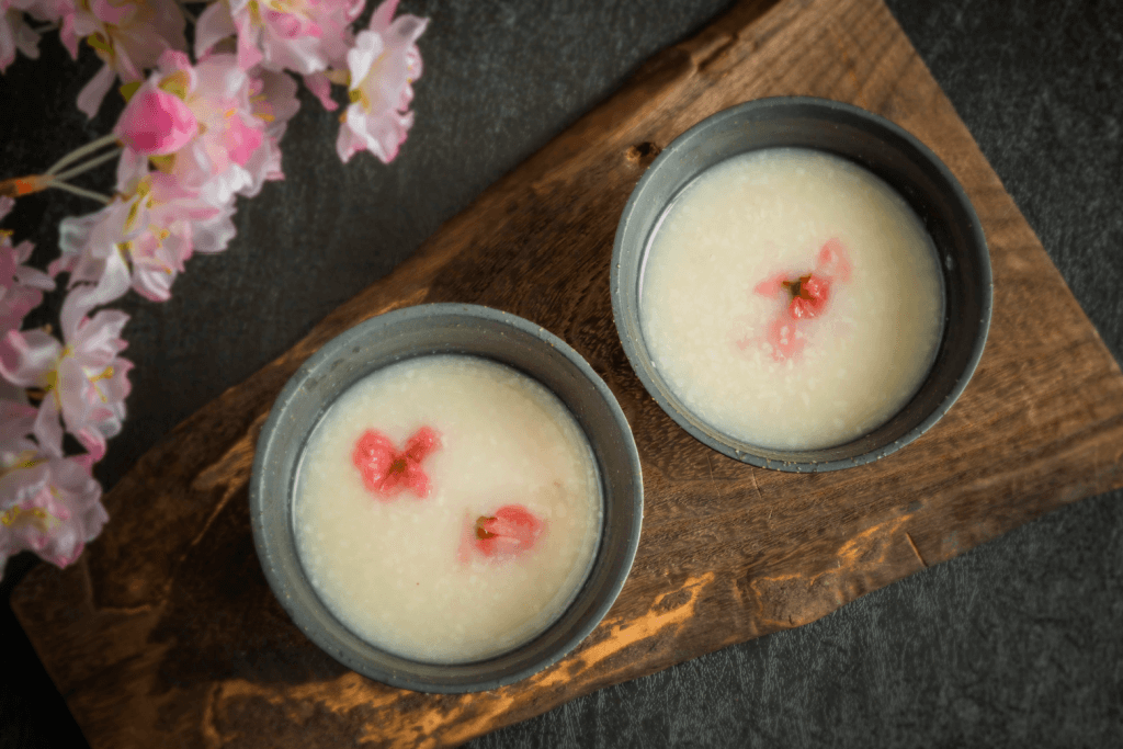 Two cups of amazake with pickled sakura inside.