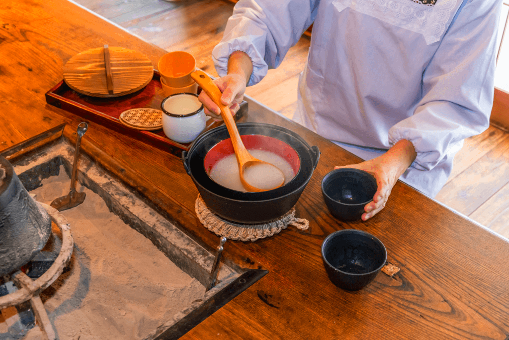 A person serving amazake straight from a hot pot.