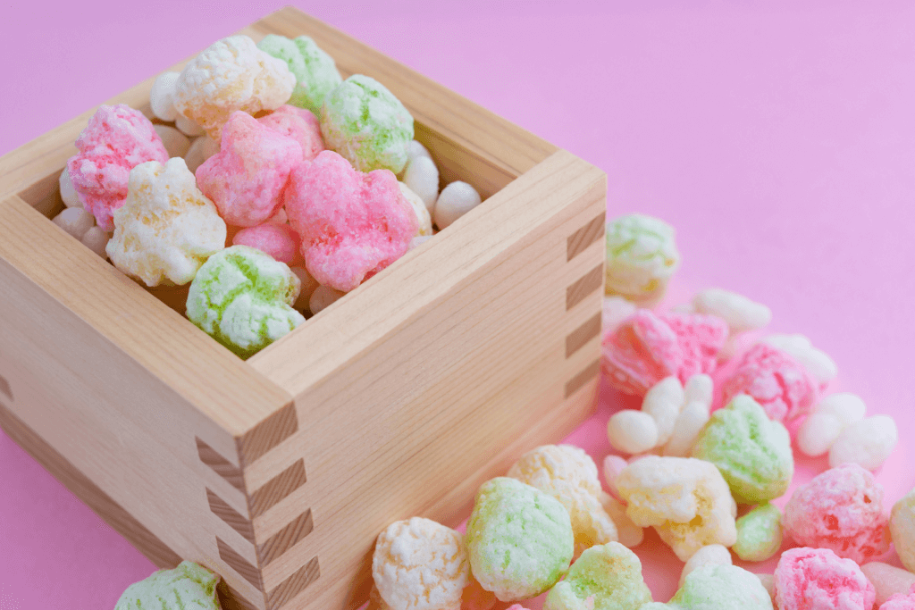A wooden box of hina arare, which are puffy rice snacks of pink, white and green.