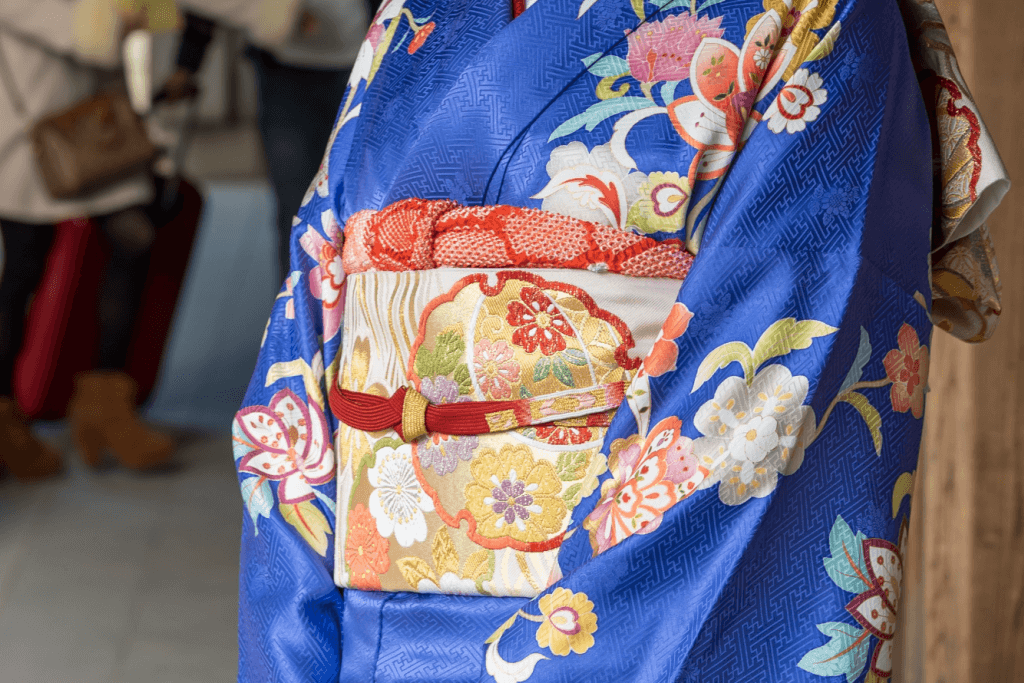 A close-up of a blue kimono with a pink obi sash.