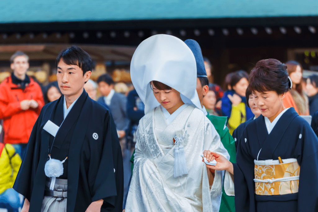 A traditional Japanese bride and groom proceeding in a Shinto ceremony. The bride is wearing a white uchikake kimono.