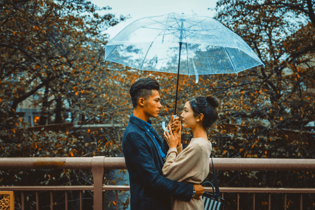 A man and a woman sharing an umbrella on a rainy day, showing that they know how to say I love you in Japanese.