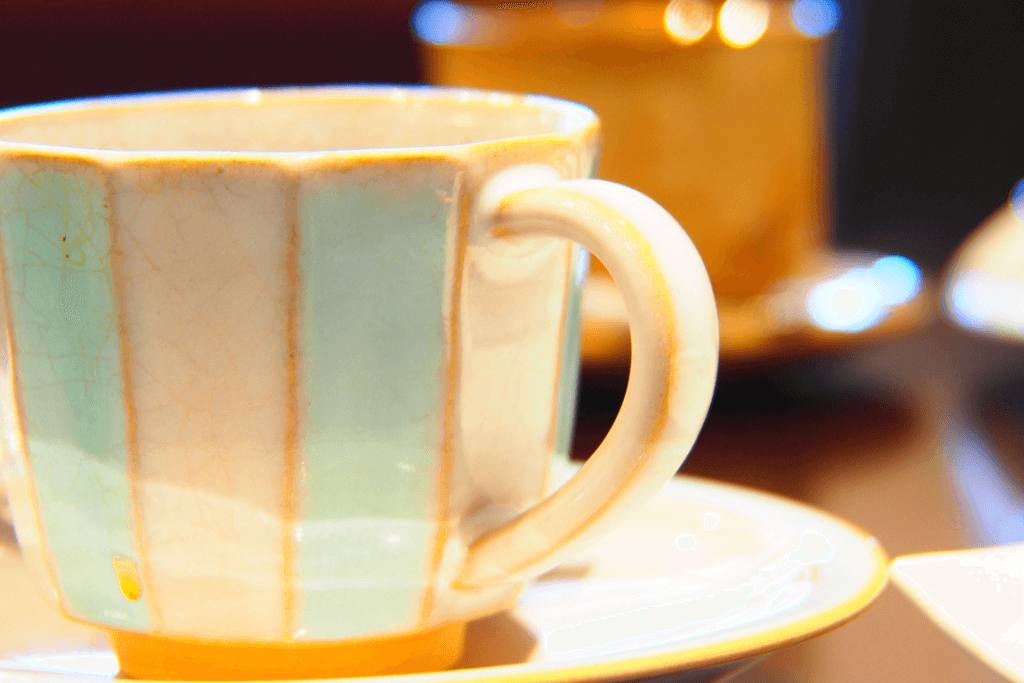 A hagi ware cup of mint and white on a saucer.