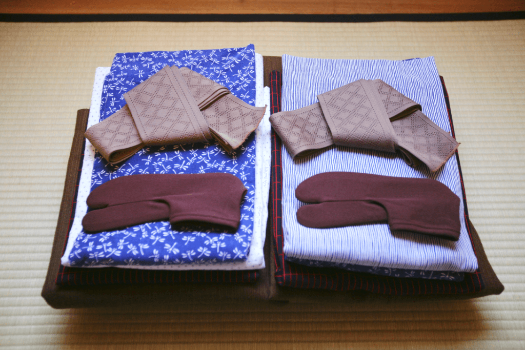 A pair of folded jinbei pajamas. They are blue and white with black and brown ties.