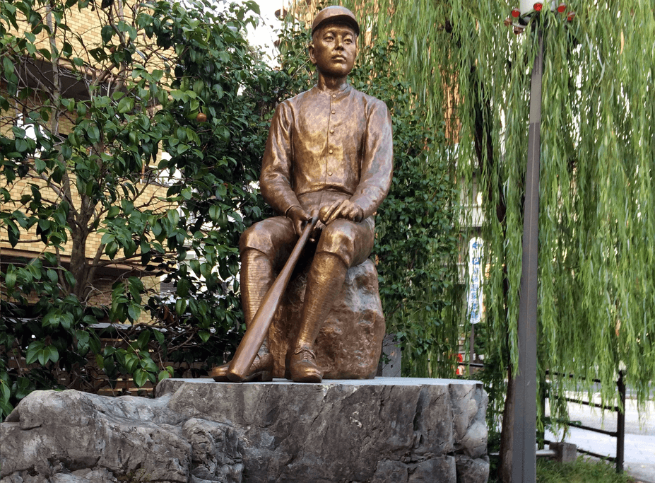 A bronze statue of Masaoka Shiki near bamboo.