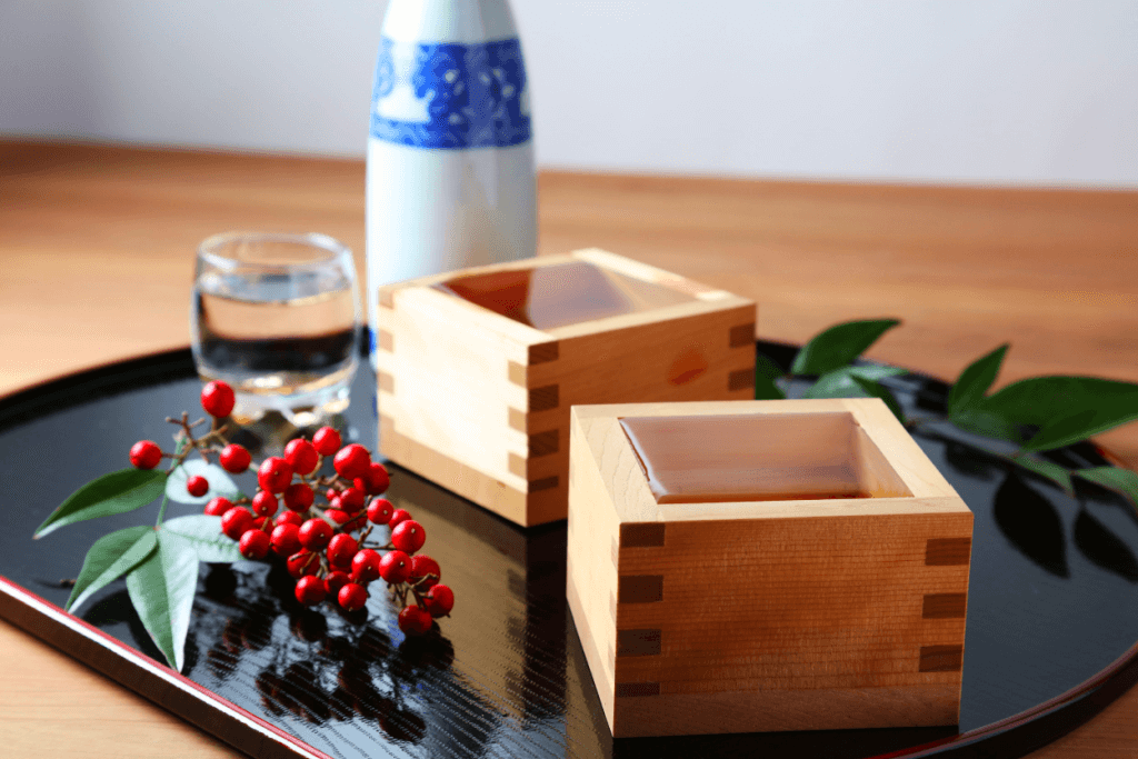 Two wooden sake cups with sake inside.