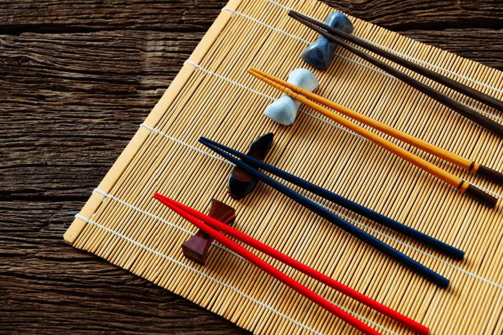 Four pairs of red, black (x2) and yellow wooden chopsticks.