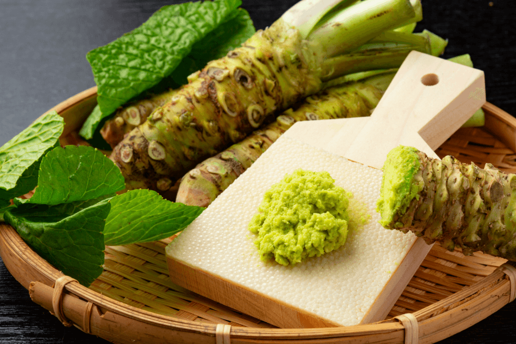 Japanese wasabi in grated and root form in a wooden basket.