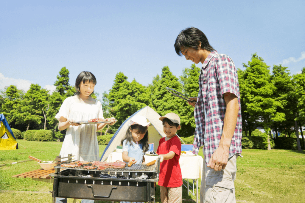 A Japanese family at a barbecue in a meadow.