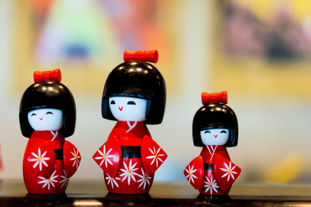 Three kokeshi dolls with white skin and red kimono. These are unusual but lovely additions to gift baskets for mom. 