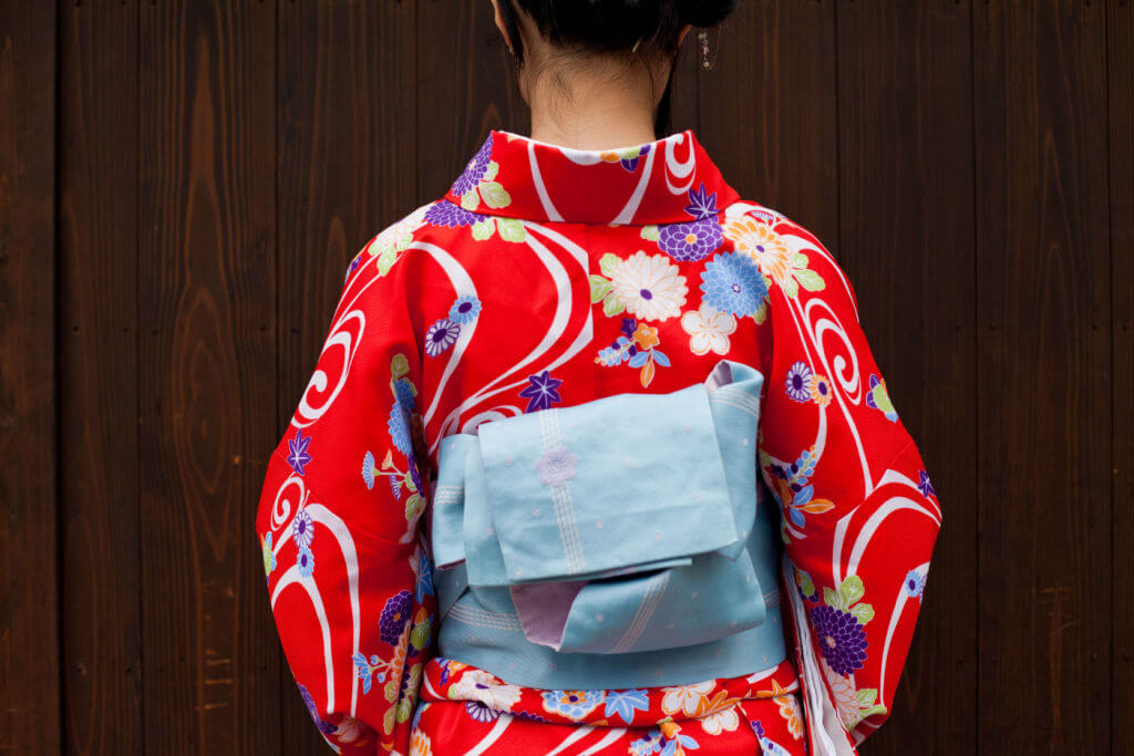 A back of a woman who is dressing in Kimono - a traditional Japanese clothes in Kyoto, Japan. It shows the back of kimono clothes and bow which is made from one fabric.