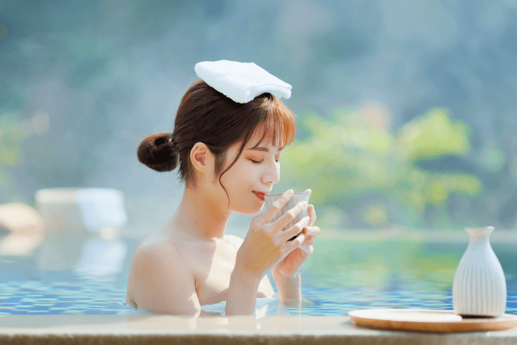 A woman drinking sake and relaxing in hot springs.