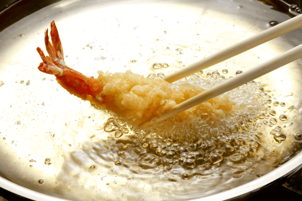 Deep frying shrimp with chopsticks.