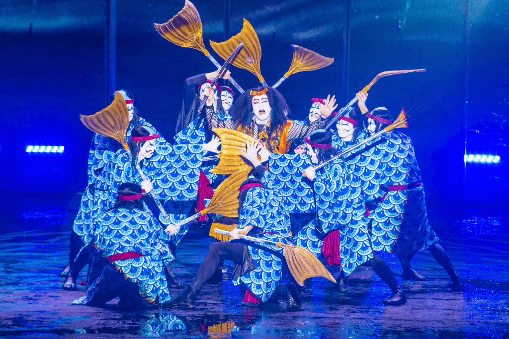 A bunch of kabuki actors on stage in Las Vegas wearing blue kimono.