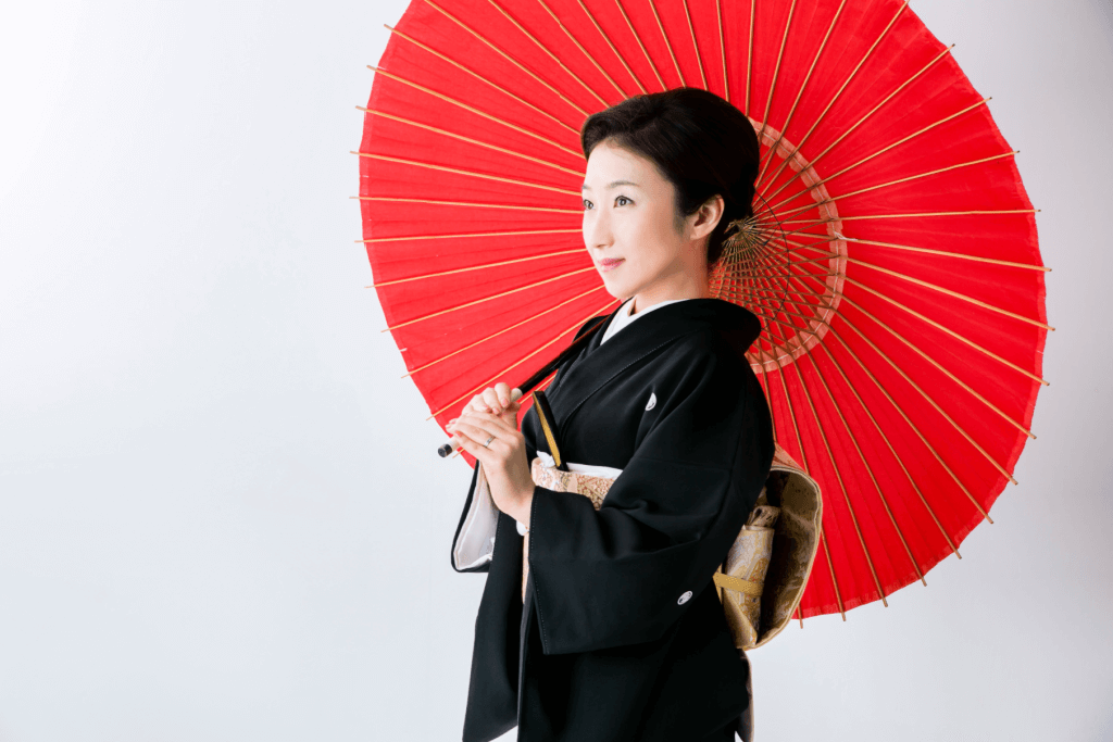 A woman wearing a kurotomesode while holding a red parasol.