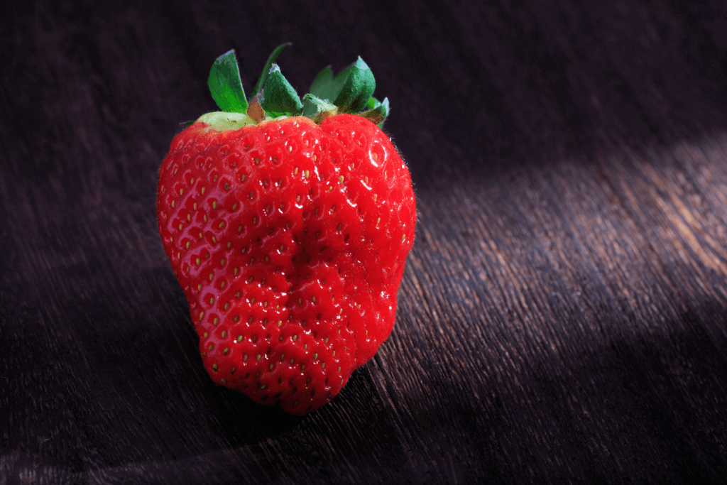 A large red Miyagi Toyonaka strawberry on a table.