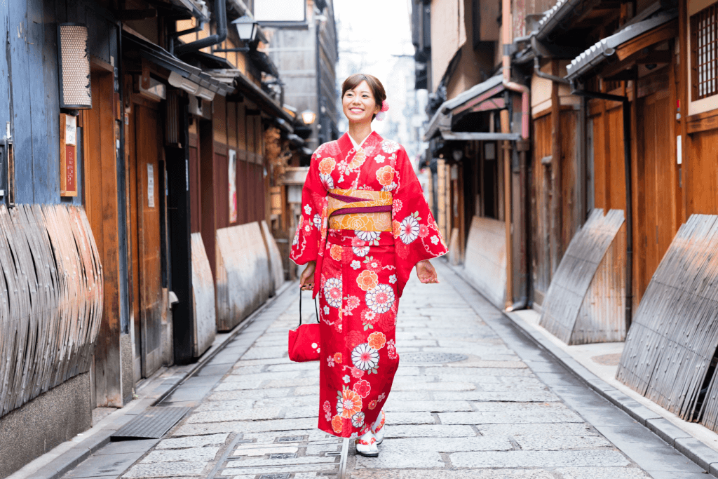 A women in a formal red kimono, walking down the street.