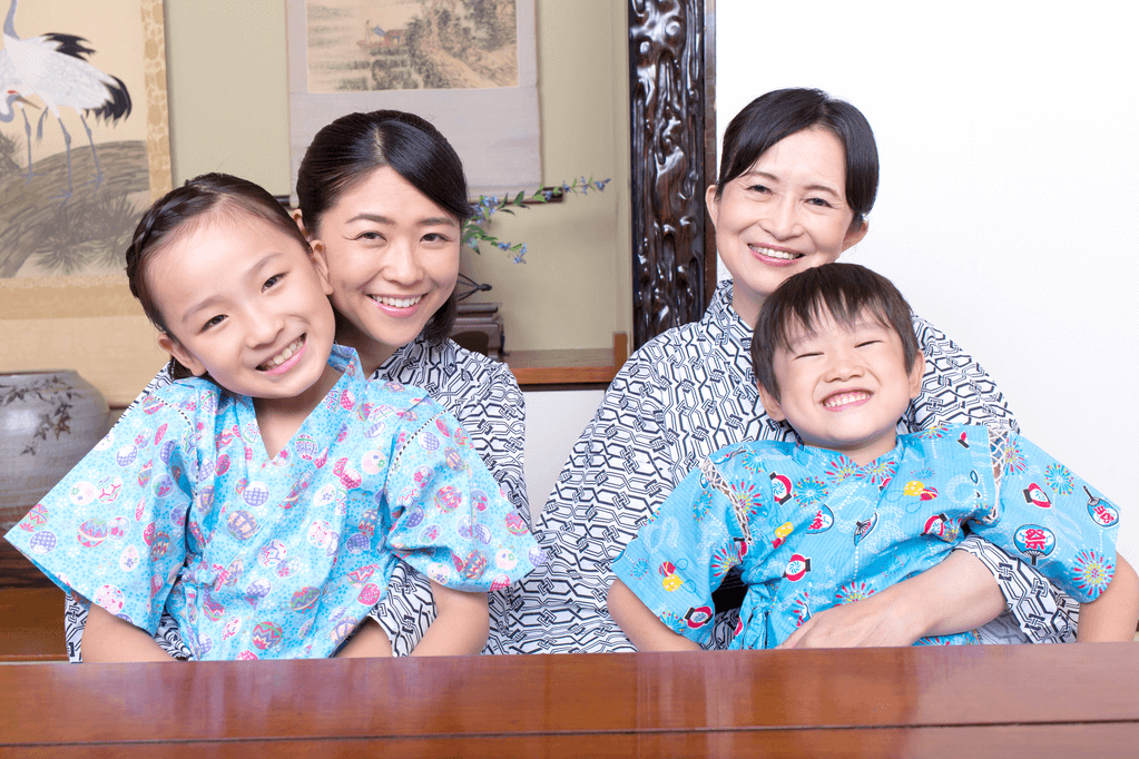 Four people (two women, two children) wearing jinbei clothing at a low table.