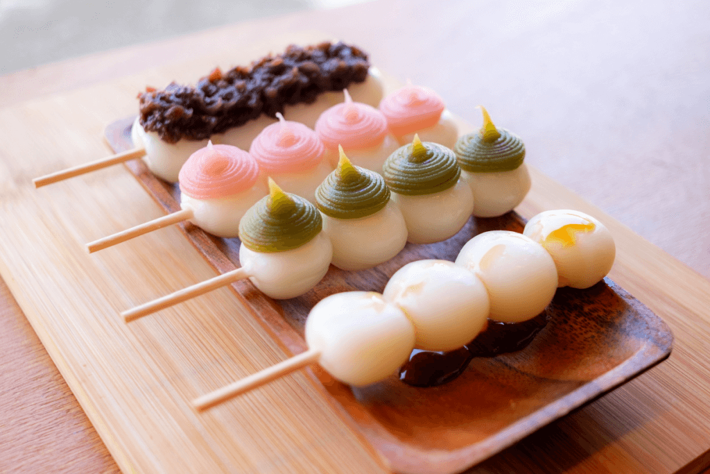 A bunch of skewered dango on a plate with various toppings.