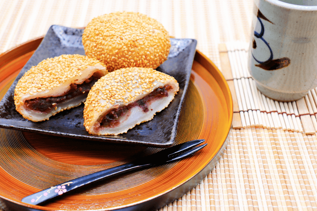 A plate of sesame rice cakes with cream and red bean paste inside.