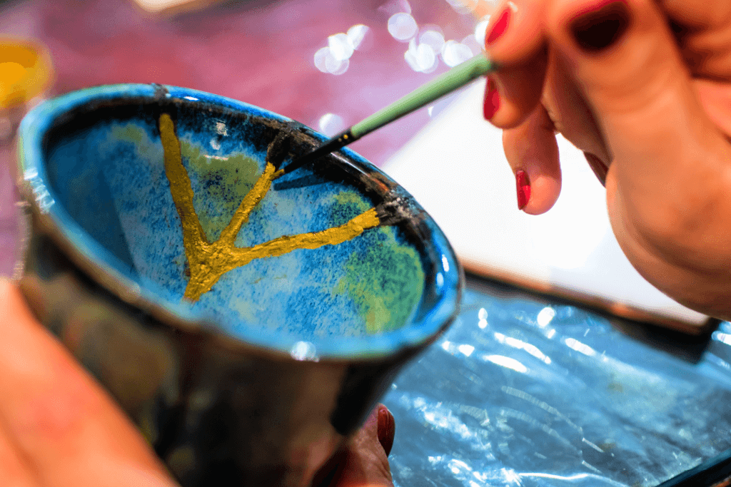Someone painting a blue kintsugi pottery bowl.