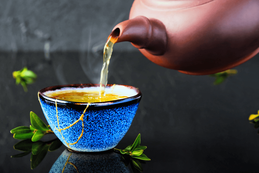 Green tea poured in a kintsugi pottery teacup.