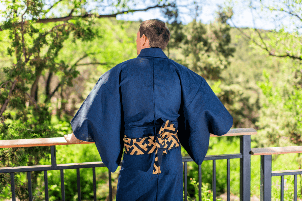 A person wearing a blue men's kimono with a patterned yellow obi.