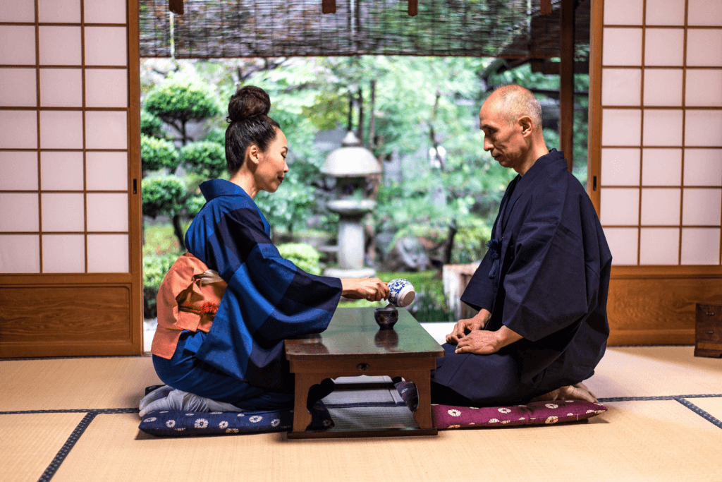 A man and a woman sitting down for tea in a traditional Japanese home.