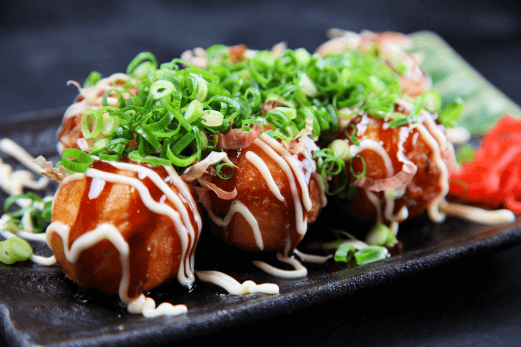 A plate of octopus balls with green onion on top.