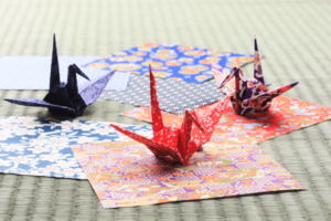 Three paper cranes of blue, red and purple.
