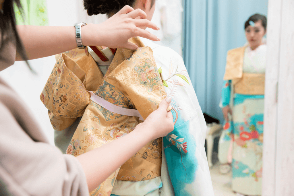 A dresser tying a young woman's kimono sash for Coming-of-Age Day.