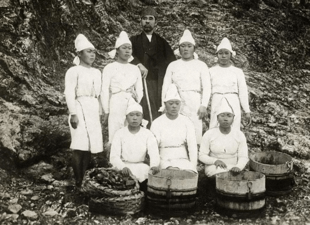 A bunch of pearl divers, dressed in white, posing for a picture.