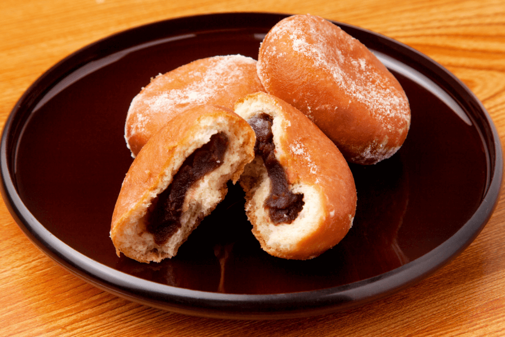 A black plate of red bean donuts.