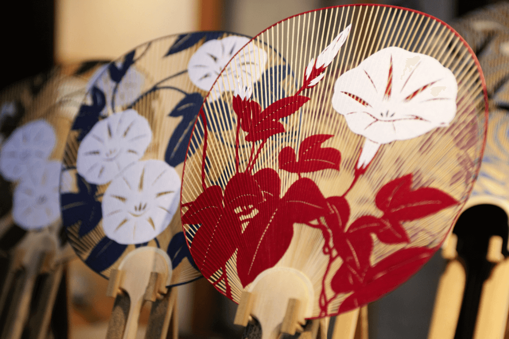 A hand-painted Kyo style Japanese fan with white flower and red leaf motifs.