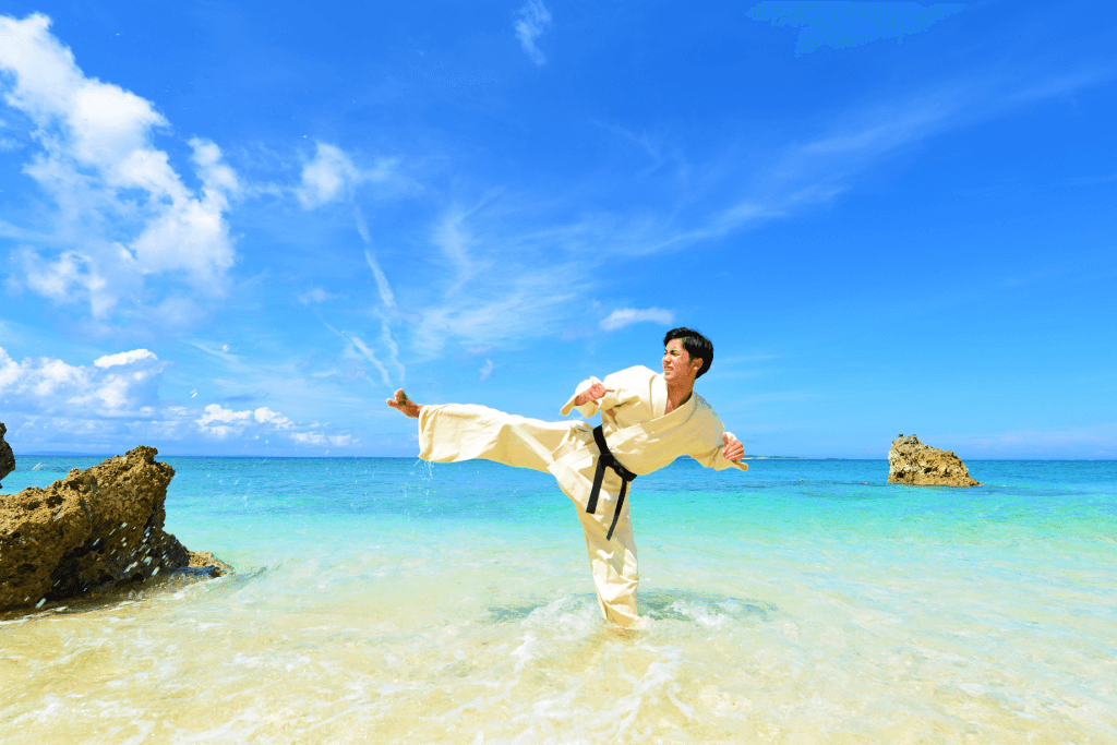 A man practicing Okinawan martial arts on the beach.