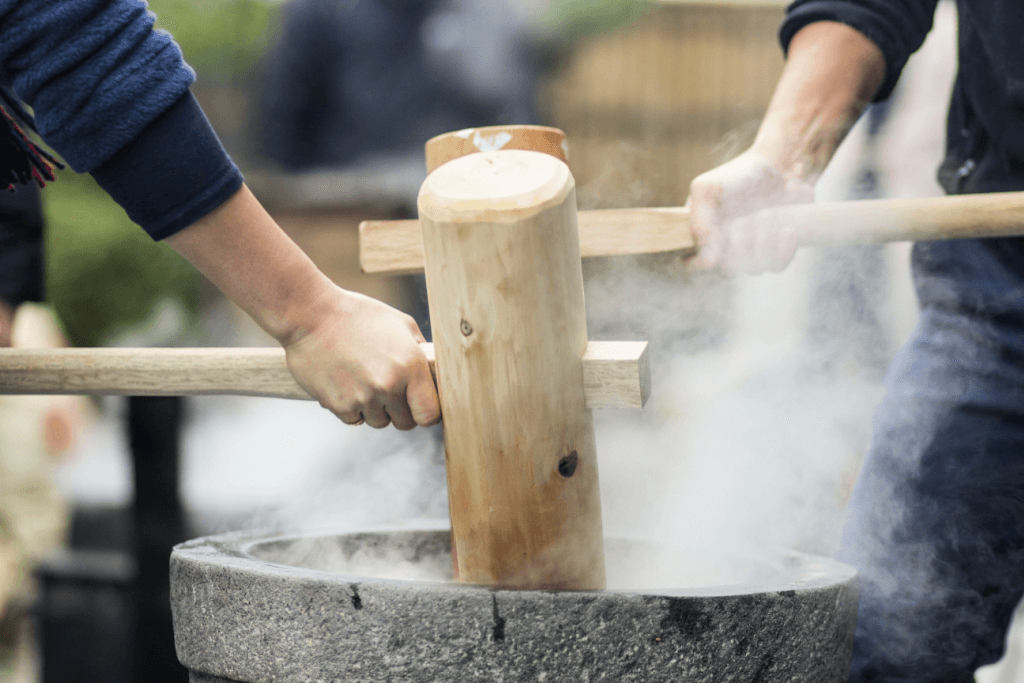Artisans pounding mochi with wooden mallets.