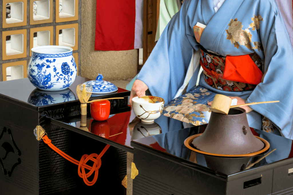 A woman in a blue kimono preparing a tea ceremony.