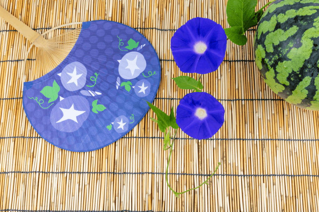 A blue uchiwa on a bamboo mat.