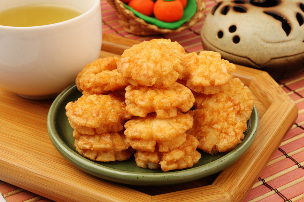 Okoge senbei sit in a small stack next to green tea