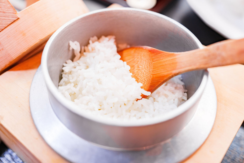 Cooked rice being scooped from a traditional Japanese kamado
