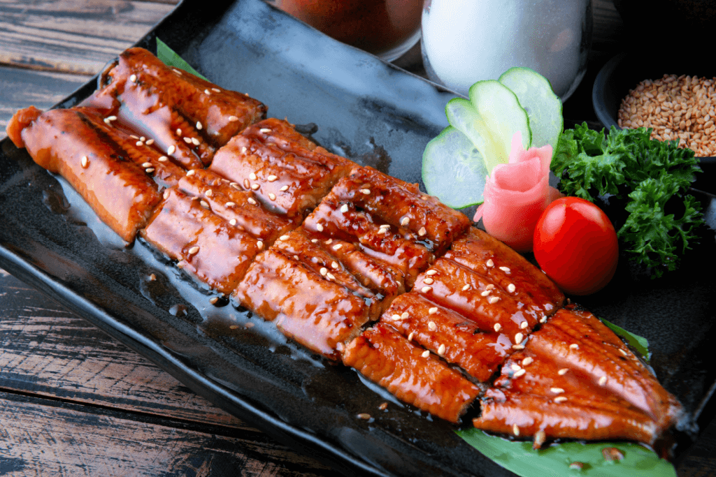 A large slice of grilled eel with sweet tare sauce on it.