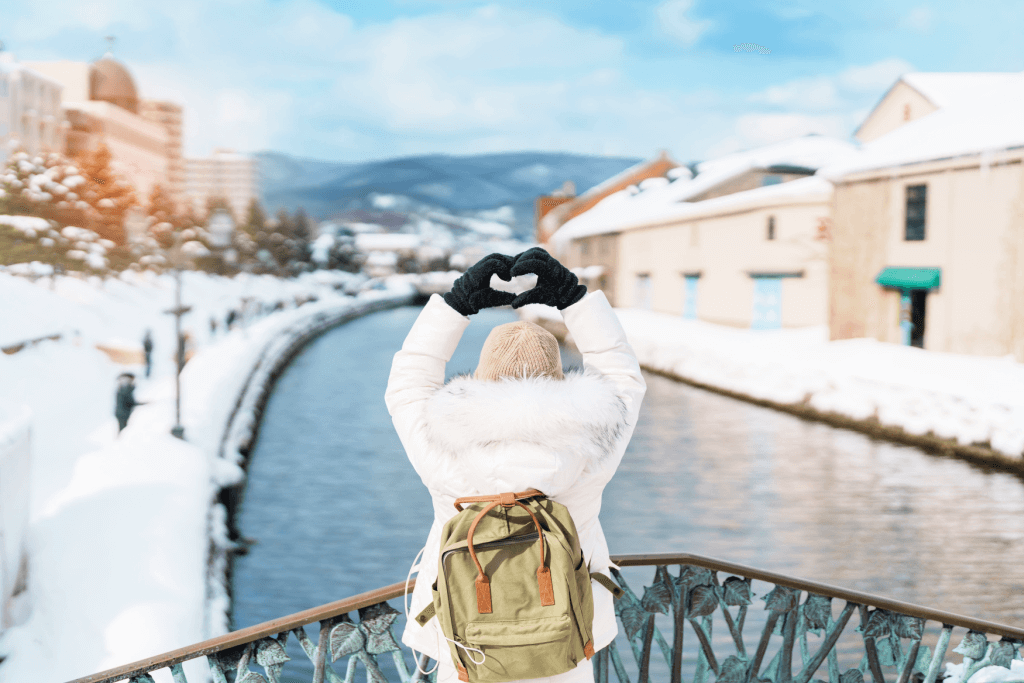 A woman making a hart sign with her hands on a bridge during happy holidays in Hokkaido.