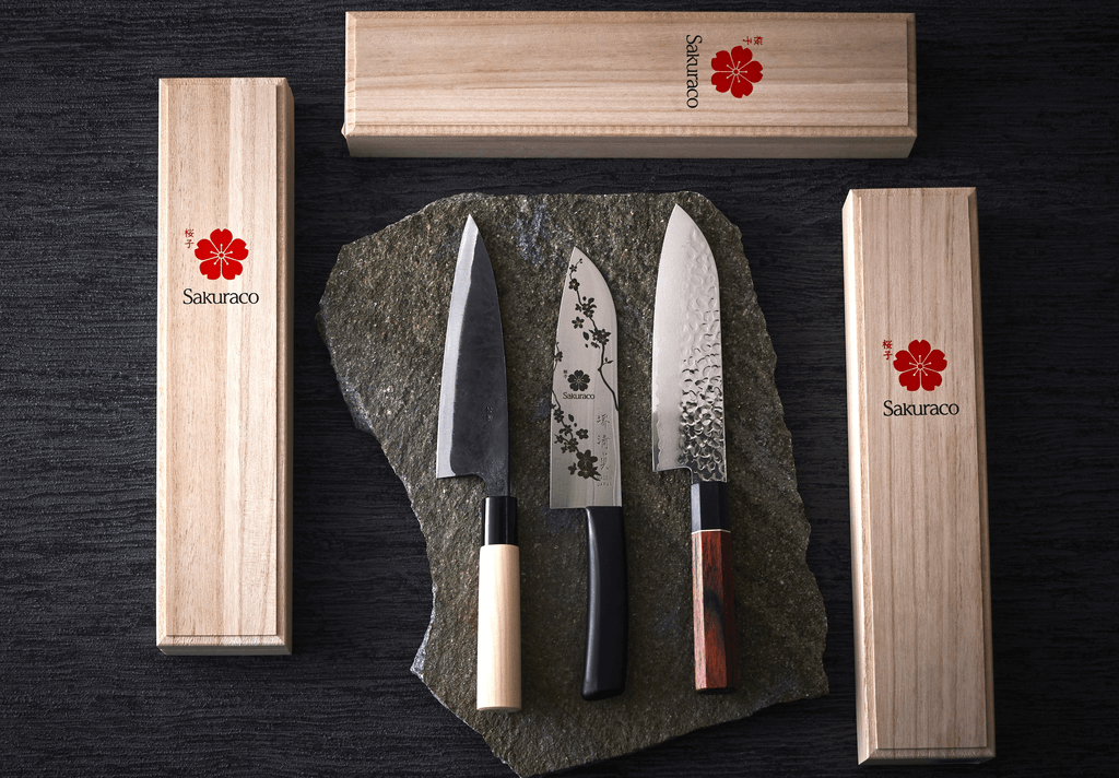 Three unique Japanese knives, surrounded by Sakuraco boxes.